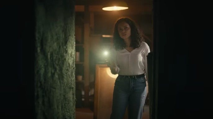 Georgina Campbell as Tess in Barbarian holding flashlight discovers basement