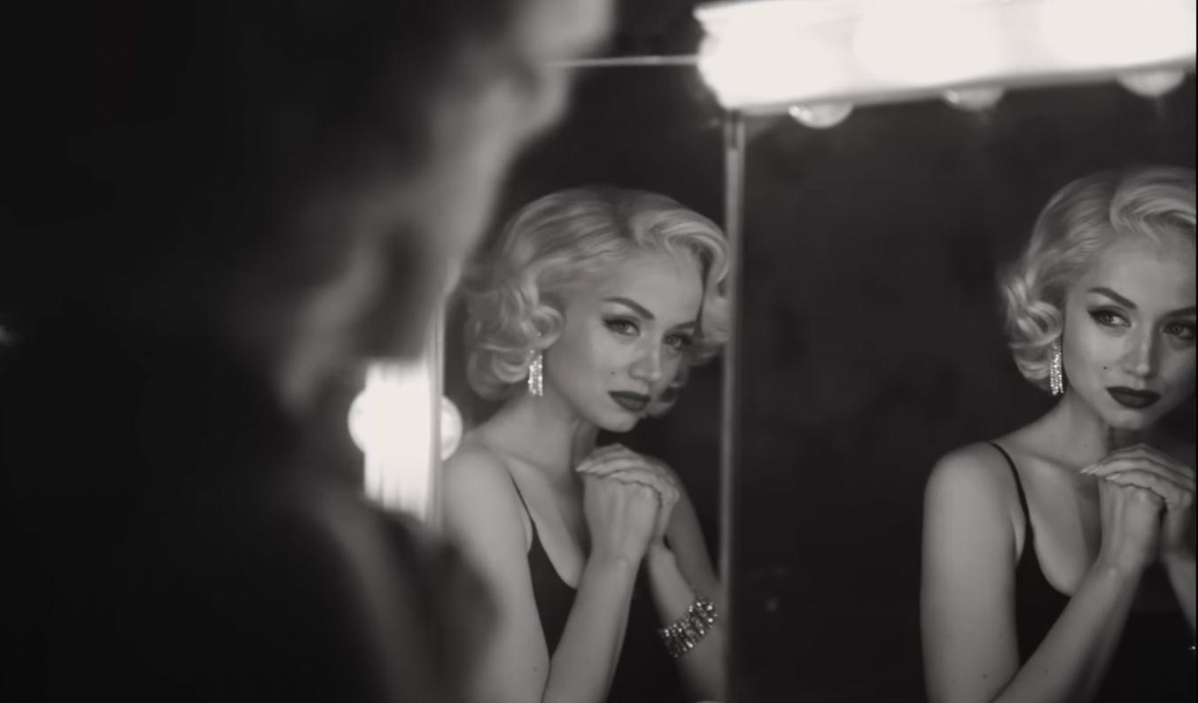 Blonde Ana de Armas as Marilyn Monroe smiling at a mirror