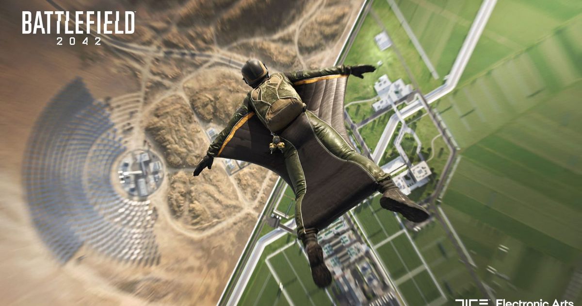 A man base jumping towards the ground, with an industrial complex below.
