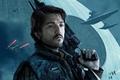 Andor Season 1 Diego Luna as Cassian Andor holding a rifle over his shoulder with ships flying behind him