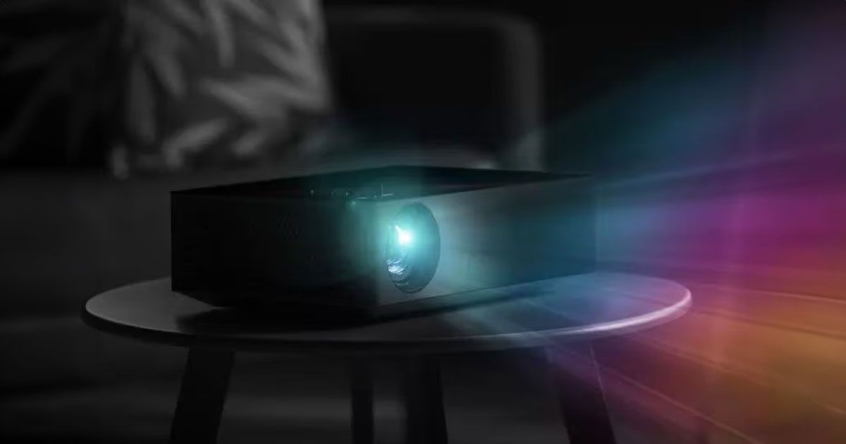 A black projector sat on a black round table projecting multicoloured lights out of its lens.