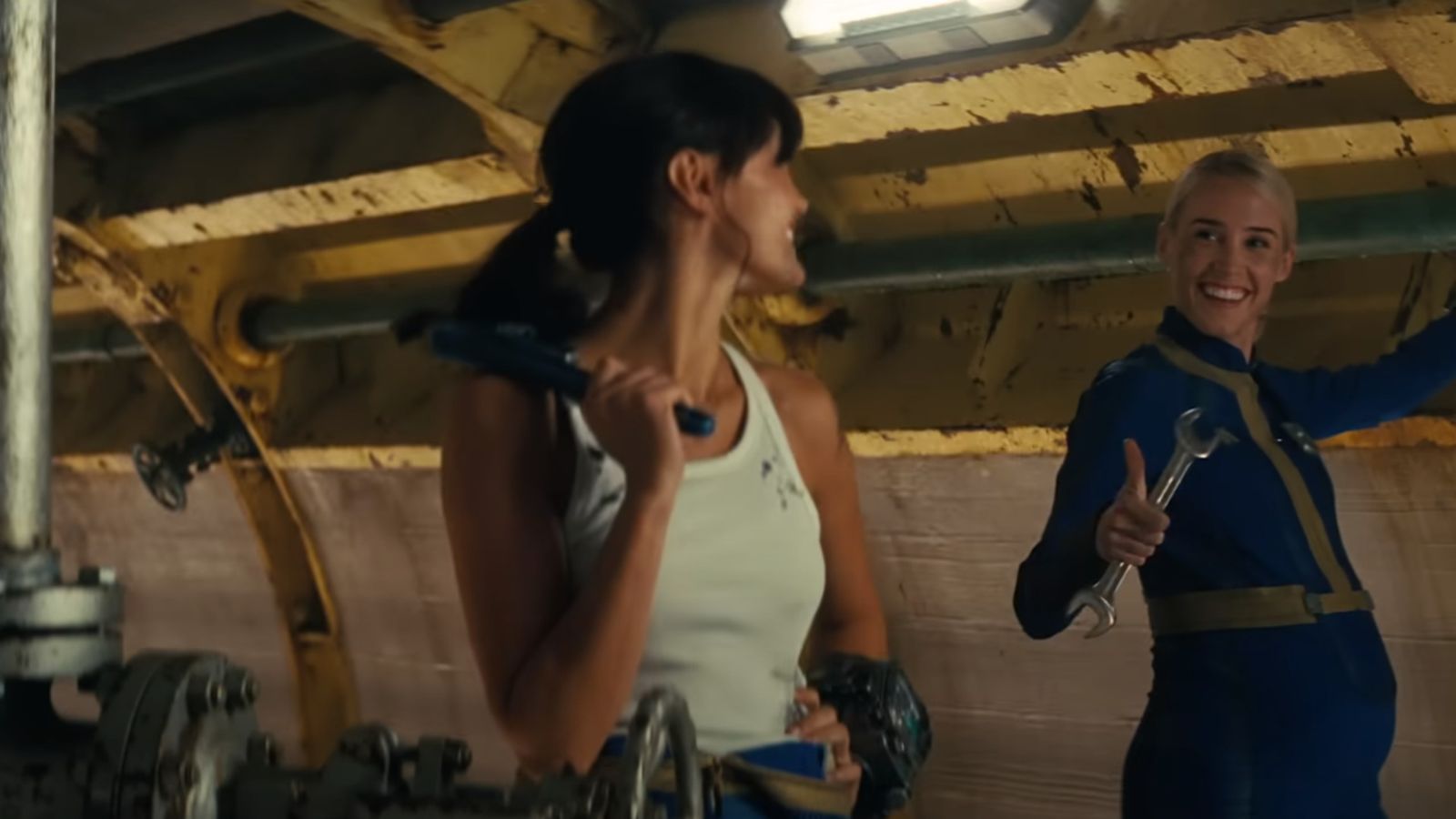 Annabel O'Hagan's Steph Harper performing maintenance duties opposite Ella Purnell's Lucy MacLean. Screenshot taken from the Fallout Official Trailer.